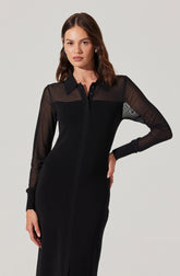 A woman is wearing a black dress with a collared neckline and long sheer sleeves. The sleeves are slightly see-through, with the upper part of the dress having a sheer yoke that extends into the sleeves. The cuffs and collar are made of a solid, opaque fabric. The dress has a fitted silhouette with a front button placket running down the center.